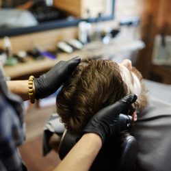 Specialist in black gloves massaging head of client in hair salon
